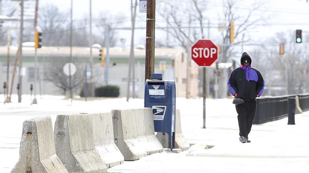 A man bundled up for the cold walks in the wind on a snow-dusted sidewalk Sunday in downtown East St. Louis.