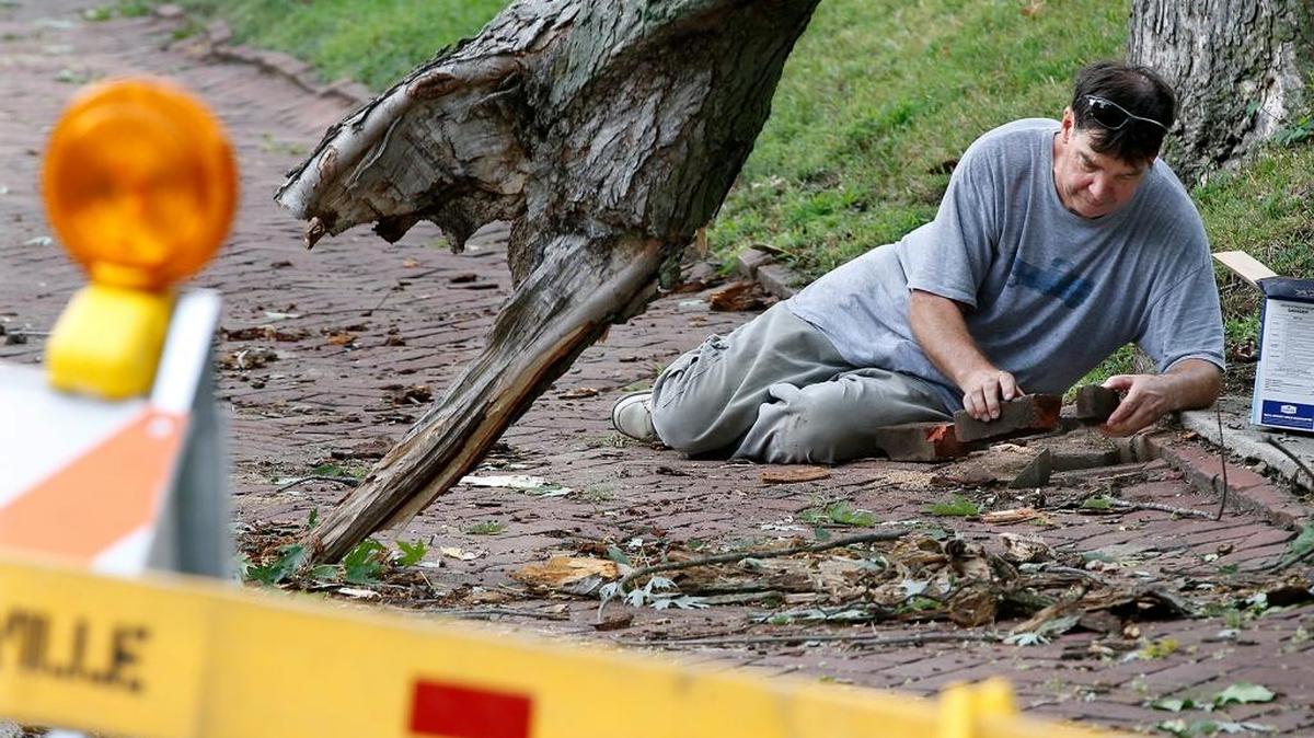 Greg Pearson pieces back together the brick sidewalk at his Mascoutah Ave. home Sunday in Belleville which was damaged from a fallen tree limb (left) which came down Saturday night during the storms in region. There was no other damage and Pearson chalked it up to “typical homeowner stuff.”