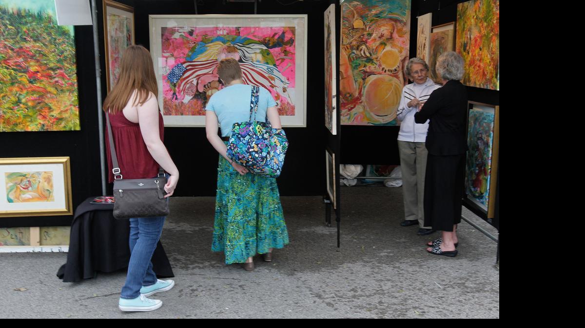 
Belleville's Annual Art on the Square kicked off Friday night with a preview party for VIPs and all artist's works on display throughout the Public Square area. The event continues on Saturday and Sunday. Patrons pause to admire the work of Yoram Gal, who has exhibited his paintings many years at Art on the Square. 
