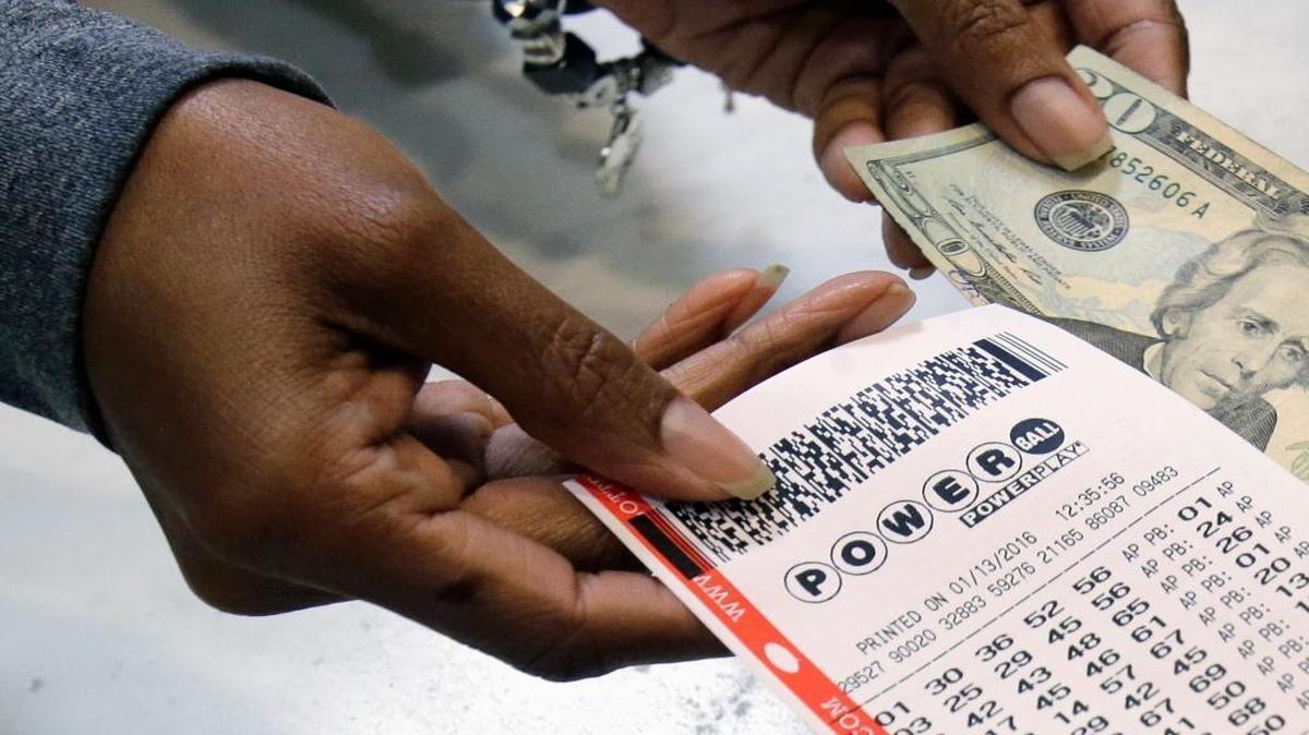 In this file photo, a clerk hands over a Powerball ticket for cash.