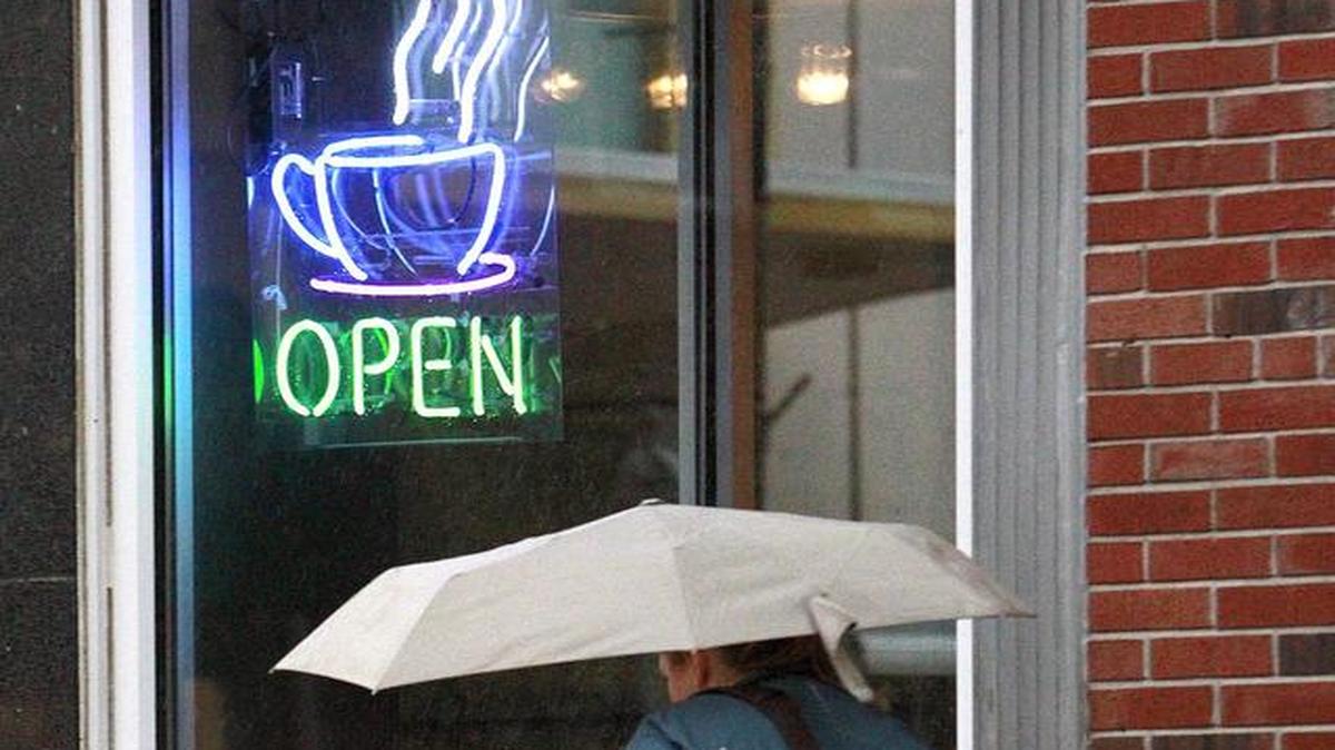 A pedestrian walks in the rain as she passes a sign for hot coffee at Junction Coffee and Yogurt Bar in downtown Belleville. Junction Coffee & Frozen Yogurt recently closed after five years of business. A planned casual restaurant will soon occupy 200 E. Main St.