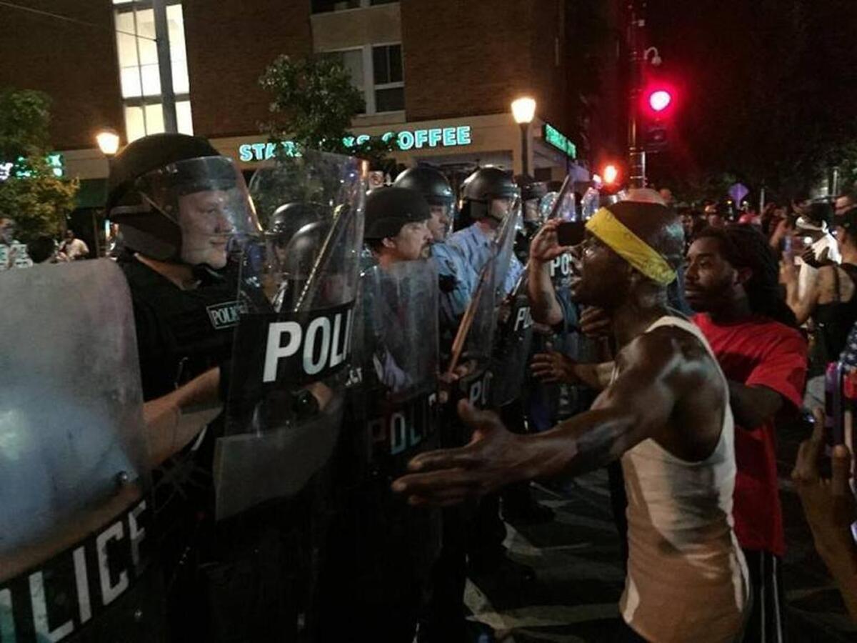 A protestor confronts a police officer in riot gear in Delmar Loop.