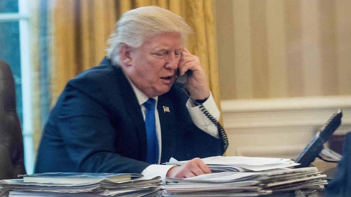 President Donald Trump speaks on the phone with German Chancellor Angela Merkel, Saturday, Jan. 28, 2017, in the Oval Office at the White House in Washington.