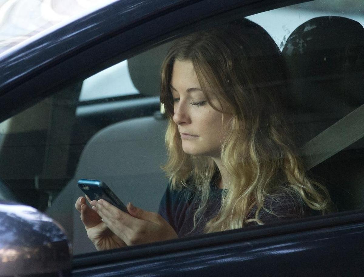 A driver uses her mobile phone while sitting in traffic. Illinois is one of 14 states that ban using a hand-held device while driving.