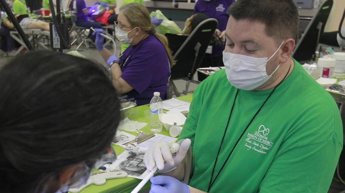 SIUE fourth-year dental student Josh Pogue (right) assists dentist Bethel Buerk as they work on a patient at the free dental clinic.