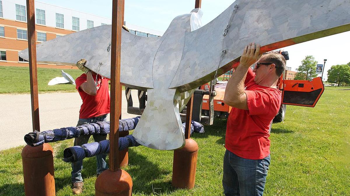 
Artist Dale Rogers (right) hoist one of his birds to be suspended from a steel frame Sunday at SWIC in Belleville.
