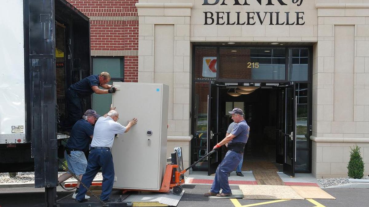 
Employees of Huffman Security, of Arnold, Mo., push and pull on a Porta-Vault as they moved bank vaults, cabinets, safe-deposit boxes and more Saturday from the old site of Bank of Belleville to their new location at 215 South Illinois Street. This heavy metal security vault weighs about 3,500 pounds, and took five men (one is behind it and not shown) to move it into position. Belleville police officers were helping guard both the old and new banks, and accompanied each of the Huffman moving trucks on the road.
