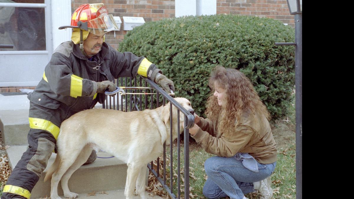 
Winston, a 1-year-old Labrador retriever, on Nov. 25, 1995, got his head stuck in a railing at 3515 W. A St. in Belleville. Belleville Fire Capt. Bobby Morrison cuts at the rail while owner Pat Erwin comforts Winston. Erwin thought her pup might have been chasing a squirrel or another dog when he got his head stuck. 

