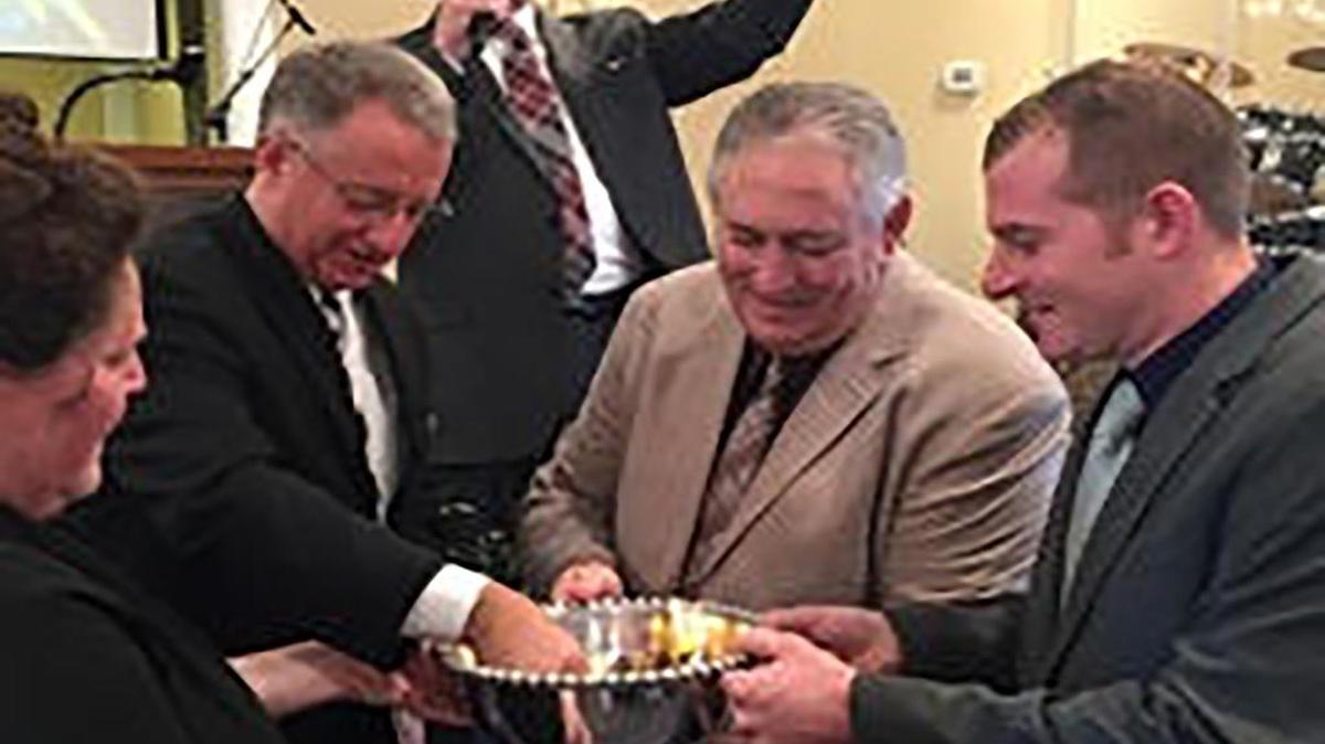 Jerry Jones, general secretary of United Pentecostal Church International, (rear) speaks to the congregation of Apostolic Revival Church in Highland on Sunday as, from left, Susan DeLong, the Rev. Frank Crossin, Delano Scott, and Nick Hoffmann burn the church’s mortgage. DeLong, Scott and Hoffmann are the church’s board of trustees. Crossin is the pastor.