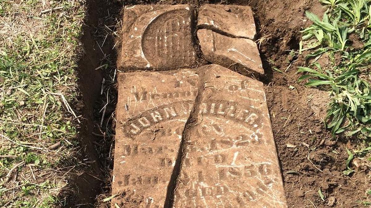 Johnny Miller’s tombstone lies in pieces at Anderson Cemetery. The stone was reset on Monday by Tim Korte and Roland Harris.