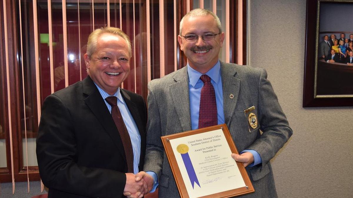 United States Attorney Stephen Wigginton, left, presents Madison County Coroner Chief Investigator Kelly R. Rogers with his office’s “Award for Public Service” commendation.