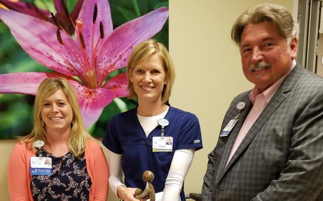 Melissa Cates, interim chief nursing officer of HSHS St. Joseph’s Hospital in Highland (left), and John Ludwig, hospital president and CEO (right), present the DAISY Award to Jody Rutz-Marti.