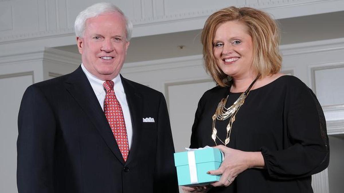 Patrick Sly, executive vice president for Emerson, presents Linda Bartlett with their Tiffany & Co. crystal apple.