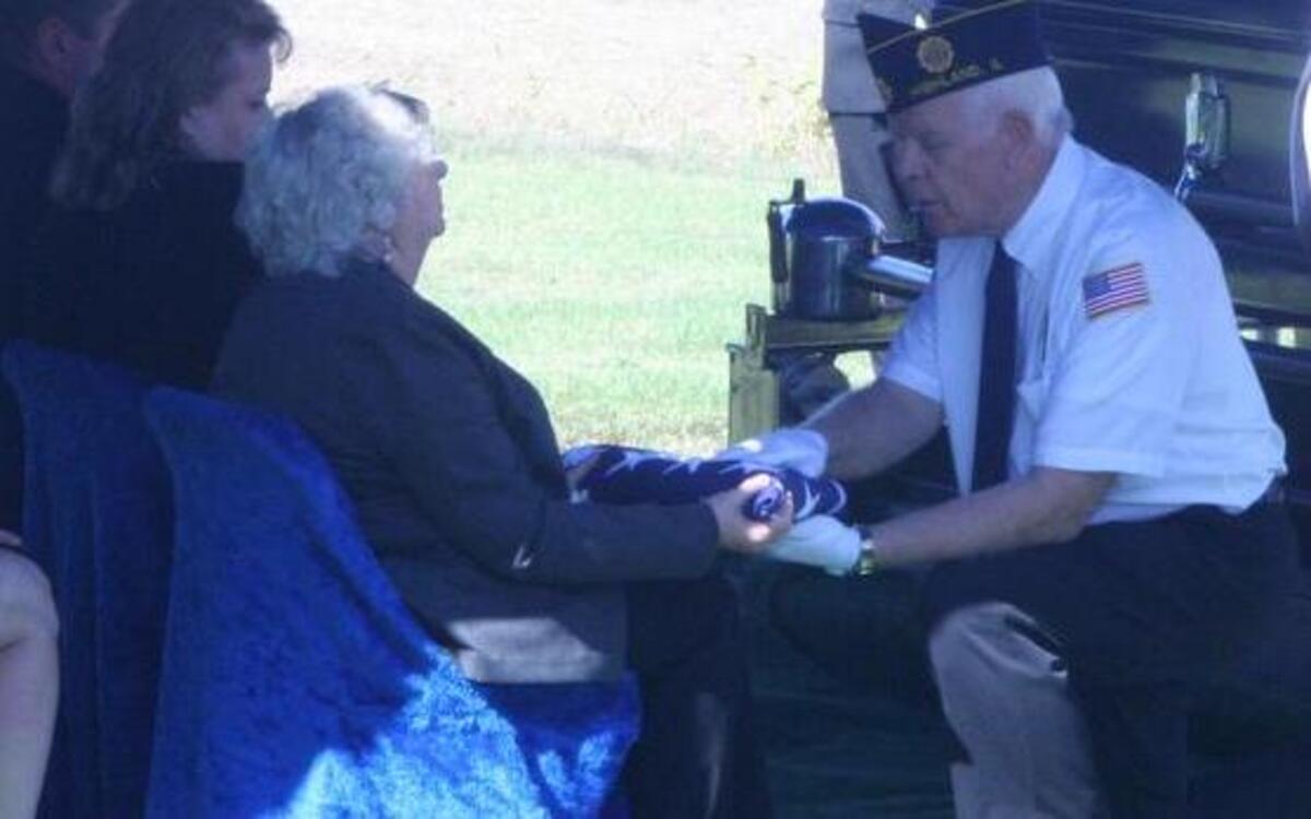 Val Buchmiller of Highland, flag folder, Legion member, Air Force veteran, presents the folded flag to the family members of a Marine veteran.