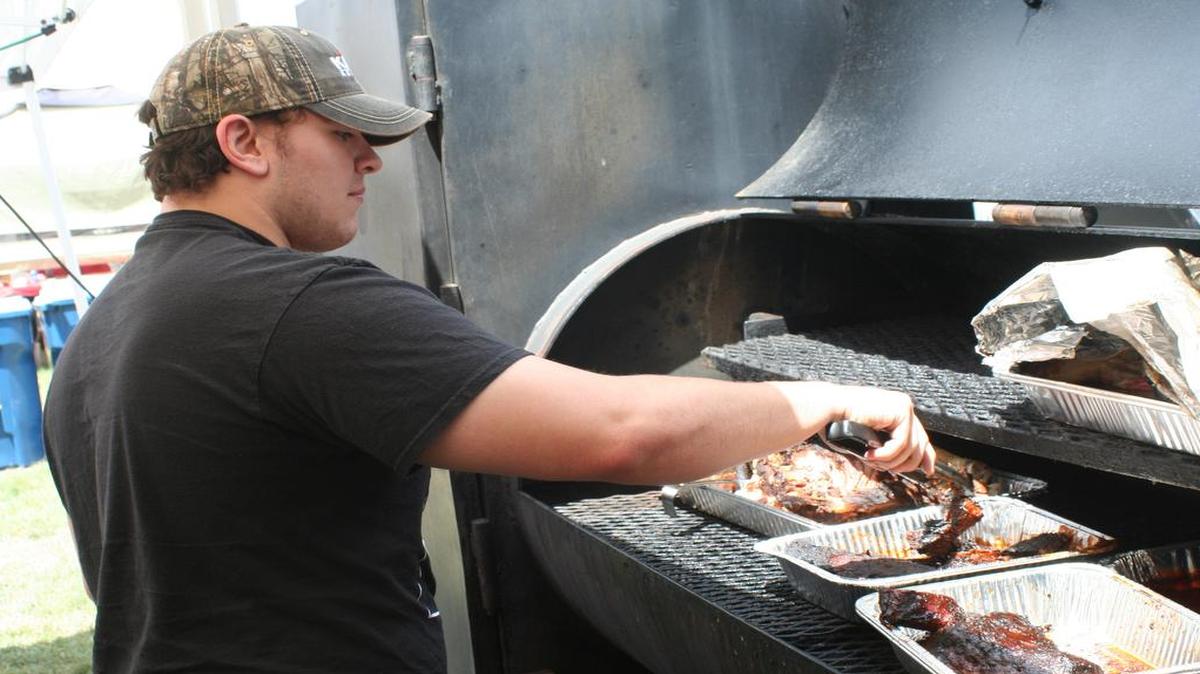 Charlie Coghill of Pork Assassin’s Backyard Barbecue Gang puts the finishing touches on his ribs and preps for the lunch time rush at Jakey in June on Sunday.