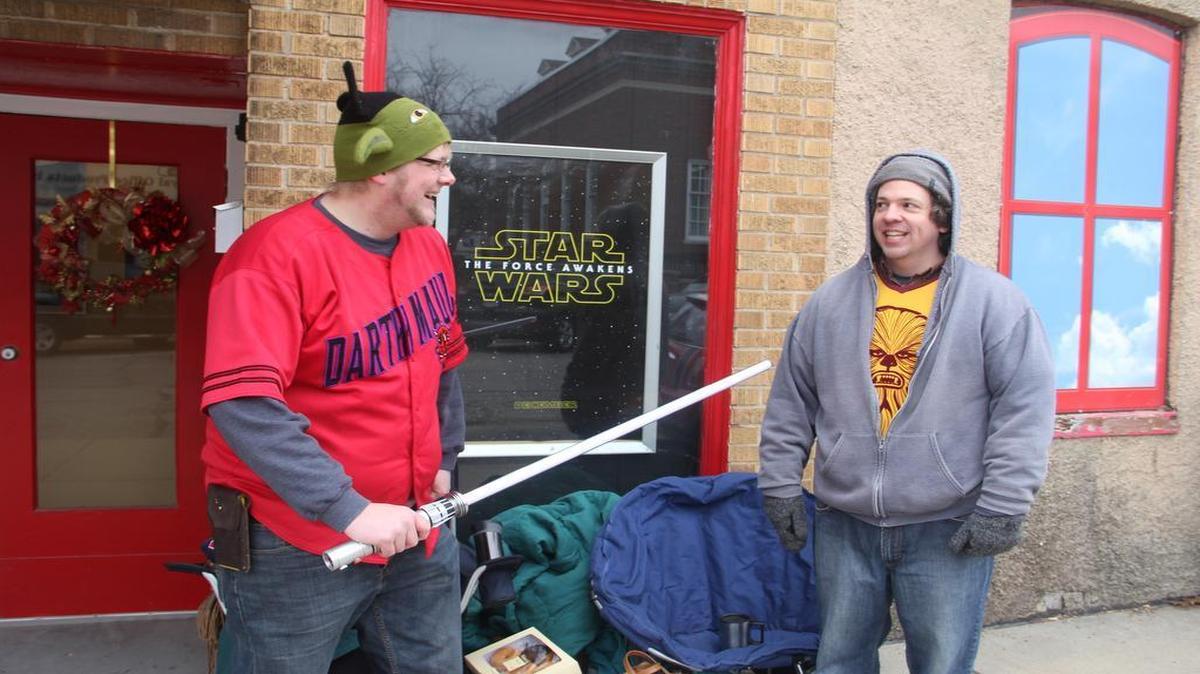 “Star Wars” fanatics Brian Knobloch of Highland threatens his friend Chad Binge of Decatur with his lightsaber in front of the Lory Theater this morning. They set up camp at about 8:30 a.m. in front of the theater before tonight’s “Star Wars: The Force Awakens” premier.