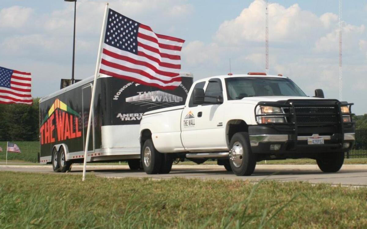 A truck pulling a trailer containing Vietnam Memorial Traveling Wall travels down a flag-lined Veterans Honor Parkway in Highland on Sept. 7.