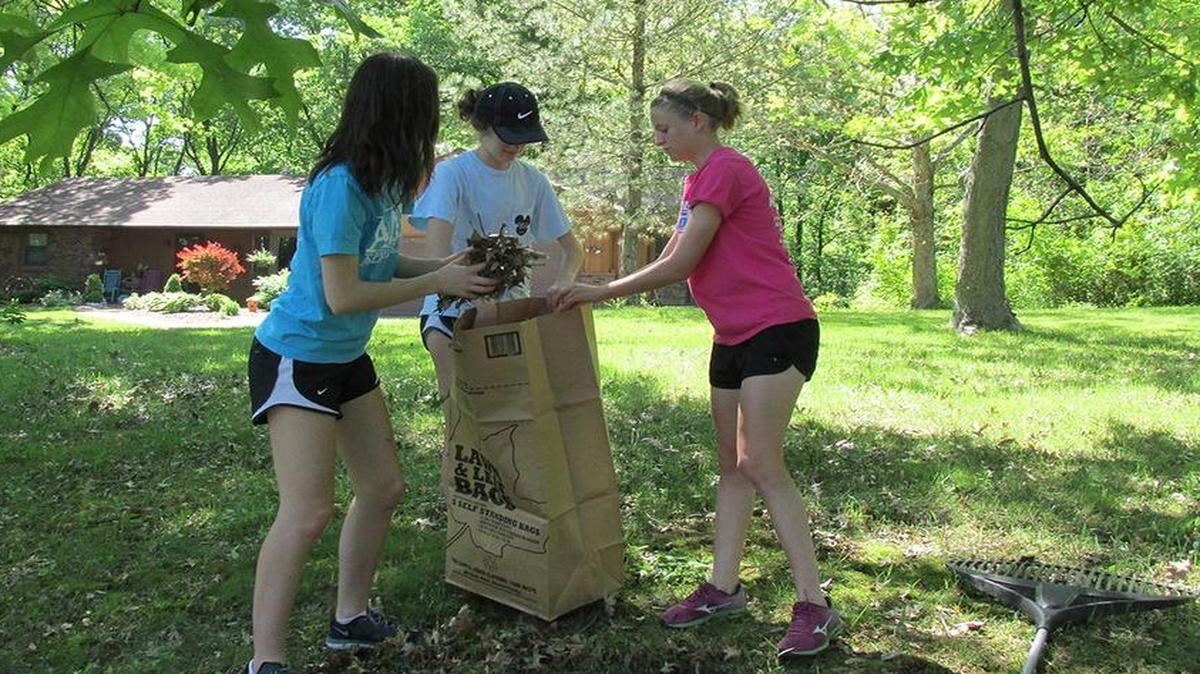 Interact members, from left, Nicole Beaubien, Keely Rittenhouse and Brittany Cunningham pick up leaves during a work day on May 7.