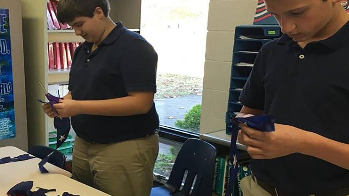 Alex Neier and Andrew Thomae cut stars out of flags for the ‘Stars for Our Troops’ program at St. Paul School.