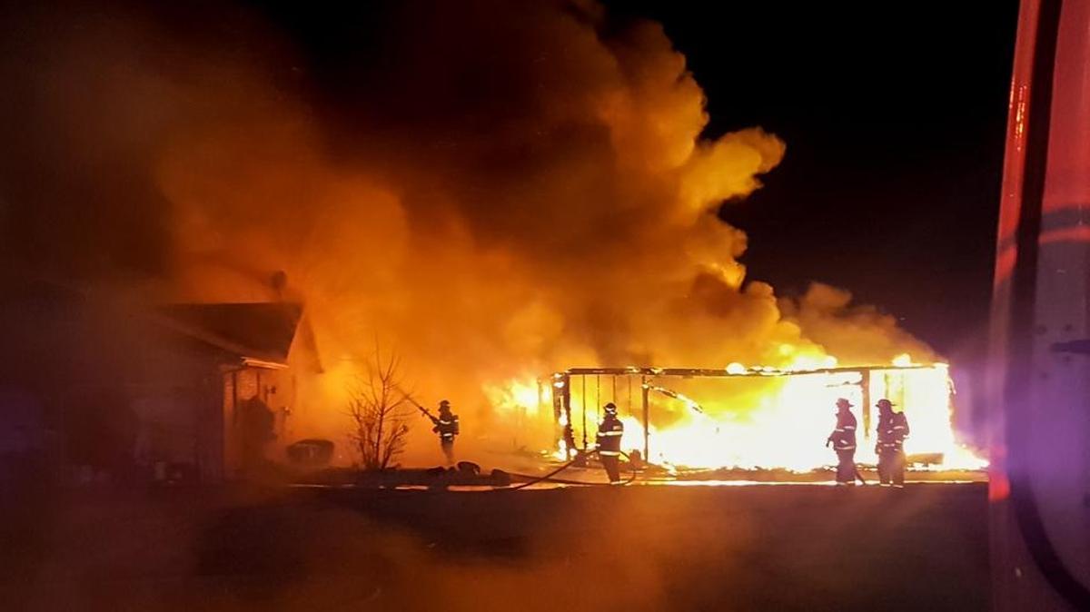 Firefighters work to keep flames from a shed fire from spreading to a nearby home Thursday morning near Highland.