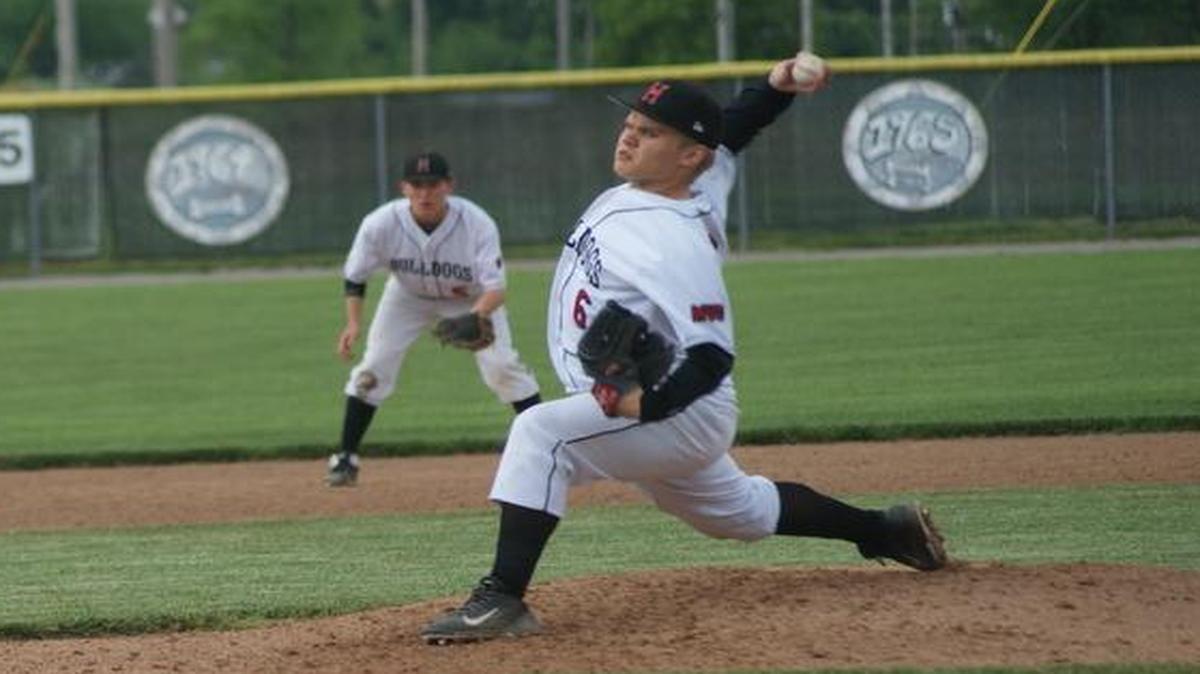 Highland senior Matt Beyer fires a pitch as senior shortstop Mike McGill gets into defensive position during the Bulldogs’ 3-2 win in eight innings over visiting Mascoutah Monday at Glik Park.