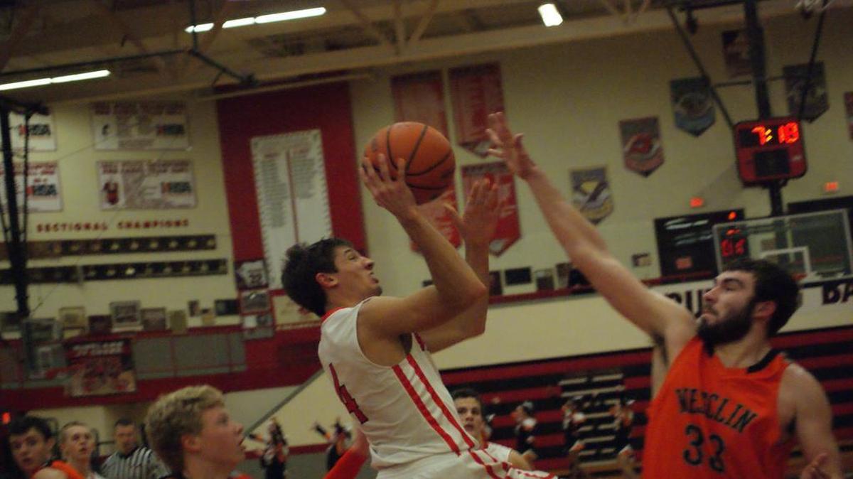 Highland senior guard Brode Portell puts up a shot on the baseline over Wesclin senior Jake Stephens during the third quarter of the Bulldogs’ 61-50 victory over the visiting Warriors Tuesday night at HHS.