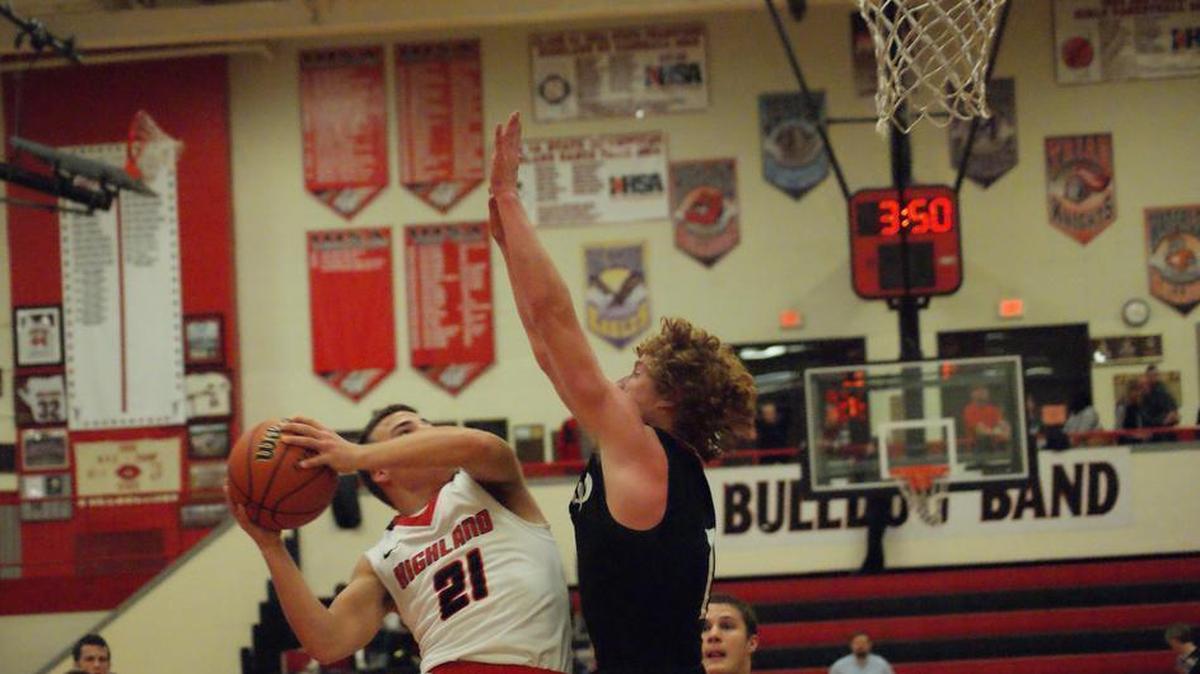 Highland junior guard Brady Feldmann puts up a tough shot near the basket while being contested by Triad senior Beau Barbour during the second half of the Bulldogs’ 53-45 home-opening victory Friday night.