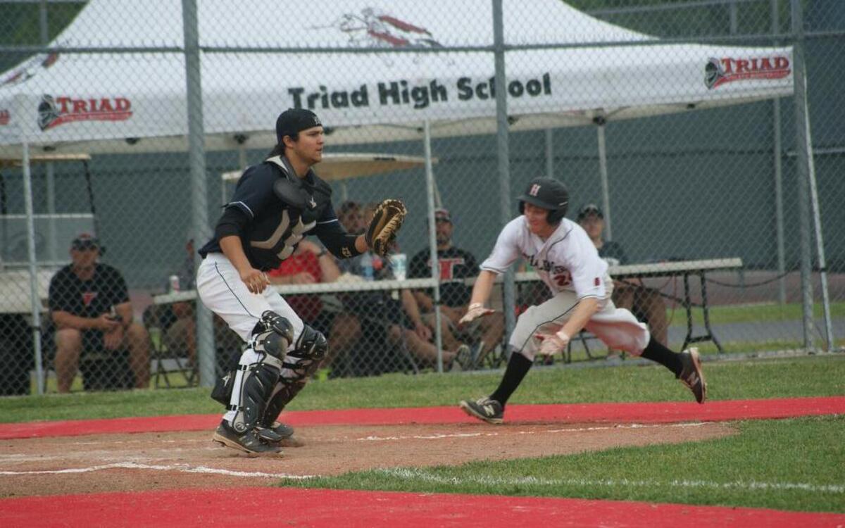 Highland junior Brock Troxell slides into home plate to score the game’s first run as Mascoutah catcher Sam Scott waits for the throw during the first inning of the championship game of the IHSA Class 3A Triad Regional on Saturday.