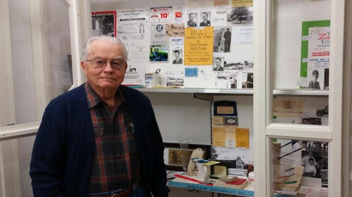 Rolland Harris, a WWII veteran, stands in front of a glass case and collage of various items he made himself at the Highland Museum, located at the end of Walnut Street. Harris is currently organizing the 44 boxes of Highland memorabilia for the museum. The museum is scheduled to open at the end of winter. An official date has not been set.