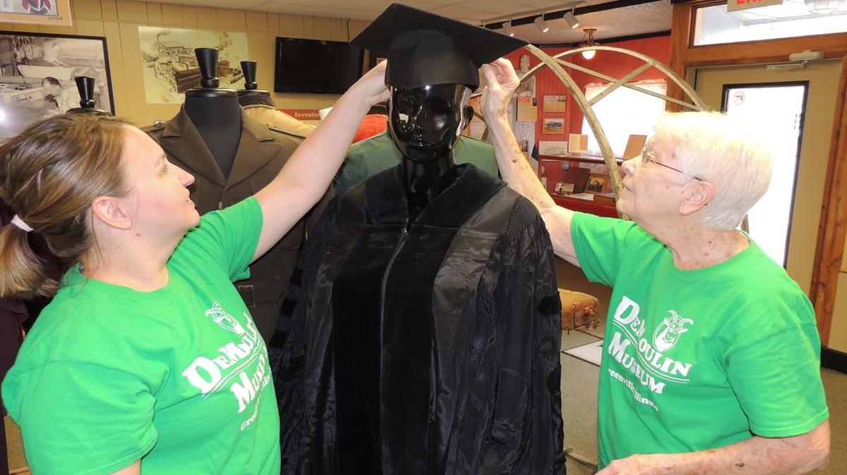 DeMoulin Museum volunteers Gina Lewis, on left, and Esther Henry prepare Ruby Dee’s doctoral gown for display.