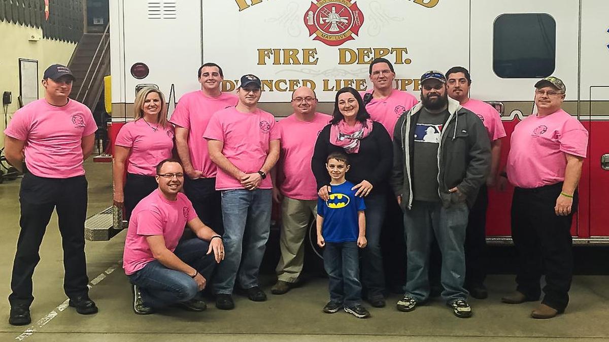 Monica Hunsdorf, joined by her husband James and son Jimmy, is surrounded by a few of the Highland Fire Department EMS IAFF Local 3672 union members, who are also displaying the pink breast cancer awareness shirts that they sold. The union donated the proceeds from their fundraiser to Hunsdorf, who is currently fighting breast cancer. From left are Tim Peters, Dawn Elliott, Zack Jenny, John Gooden, Danny Ramsey, Jeremy Brown, Steve Clayton, Anthony Perez and Dennis Frailey.