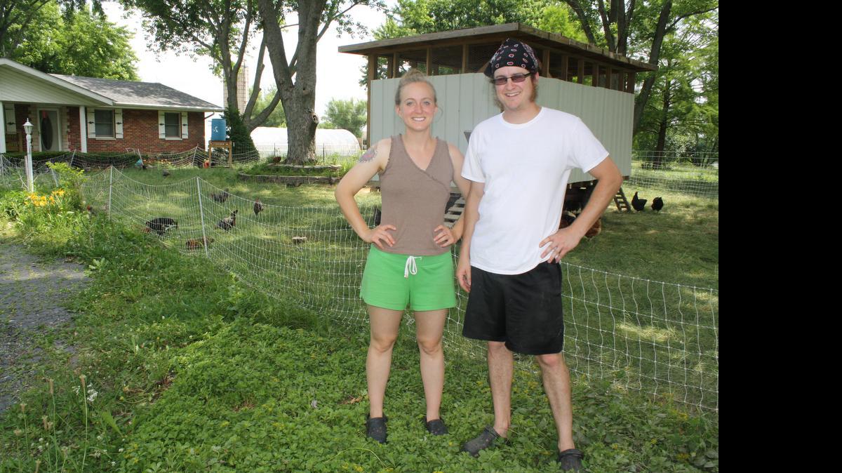 
Alicia and Josh Davis stand in front of their home and farm in Pocahontas. Behind them is the Eggmoble that Josh built to move the laying chickens weekly around the 10-acre property.
