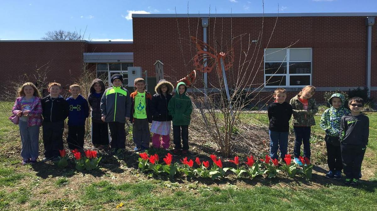Alhambra Primary students stand among their tuplips in the school’s ‘Butterfly Bed.’ From left are Aubree Schellenger, Gavin Donahue, Noah Cooper, Wyatt Choat, Trent Hediger, Adam Gillison, Calliope Smith, Adin Roach, Kevin Huckleberry, Ada Jefferson, Teyton Henkhaus and Andrew Winfree.