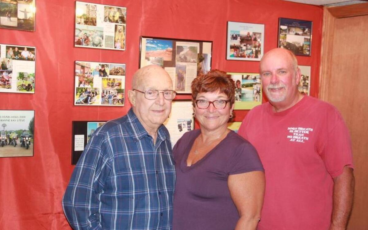 
Don Hundsdorfer, along with his daughter, Kay, and son-in-law Rex Whitecotton, stand in front of a display showing some of the many motorcycle trips they have taken over the years.
