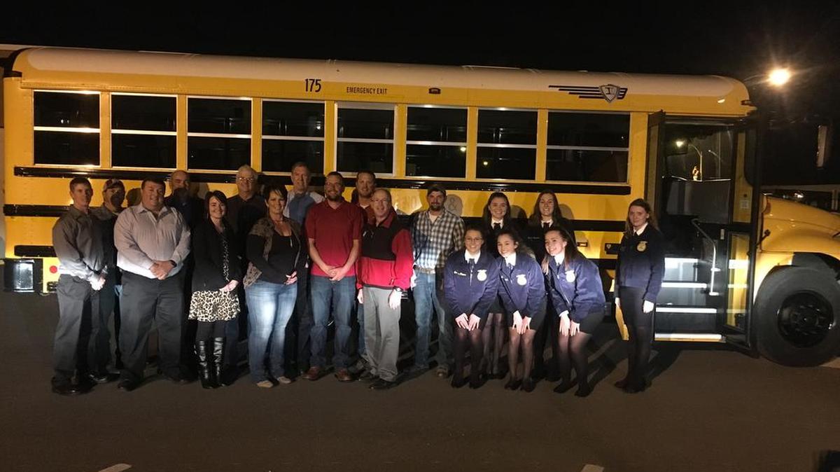 Highland FFA and alumni stand in front of the new FFA activity bus with the Highland School Board. The alumni recently donated the bus to the organization.