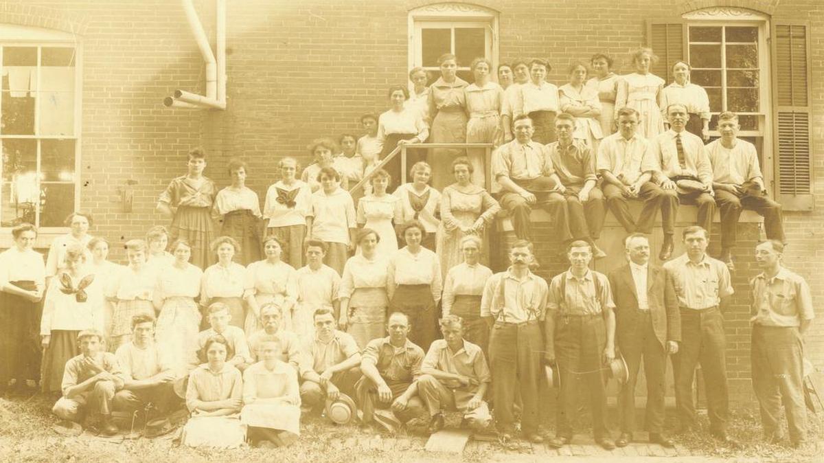 Employees of Highland Embroidery Works gather outside the building 1917. Lorna (wife of Roland) Harris’ great uncle, William Buettner, one of the stitchers, is second from the left in the photo in front row, and her great aunt, Lena Buettner, her brother’s “Bobbin’ girl,” is on the top porch, sixth from right.