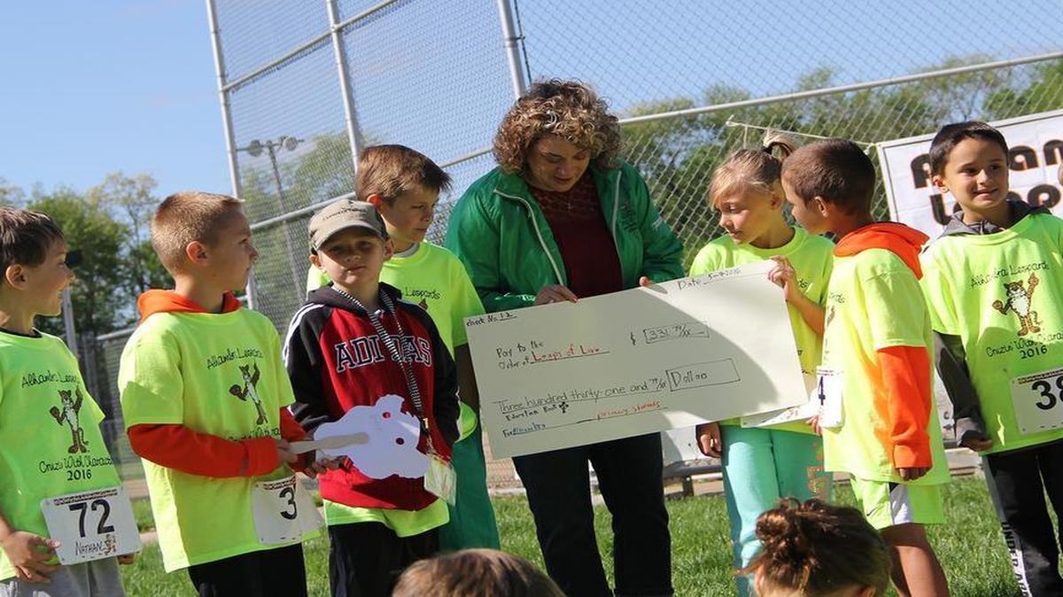 Alhambra students donate to Leaps of Love: For the “Character” part of the annual Alhambra Primary Cruisin’ with Character Mini-Marathon, students fulfilled service projects for the school and community. In February and March, the first character project was the “Taking the Challenge” program, which was designed to reduce the amount of time students and families spent using media and reduce exposure to media violence. In April, classes took turns visiting the residents at the Hitz Memorial Home. Some classes made door decorations for the residents, sang to the residents, or read to the residents. Students also collected pennies for Leaps of Love, a Highland-based organization dedicated to supporting families and children with childhood brain tumors and late affects of childhood cancer. Each week during the month of April, the bank in Alhambra would total up the pennies. Students had set a goal of raising $300 and ended up raising $331.72. Pictured Traci Riechmann of Leaps of Love accepts the check from students. Studens pictured, from left, are Nathan Aranowski, Brandt Mansholt, Reid Burrows, Isaiah Jump, Traci Reichmann, Kenzie Ingram, Trey Kronk, Tyler Hunsche and Titus Jefferson.