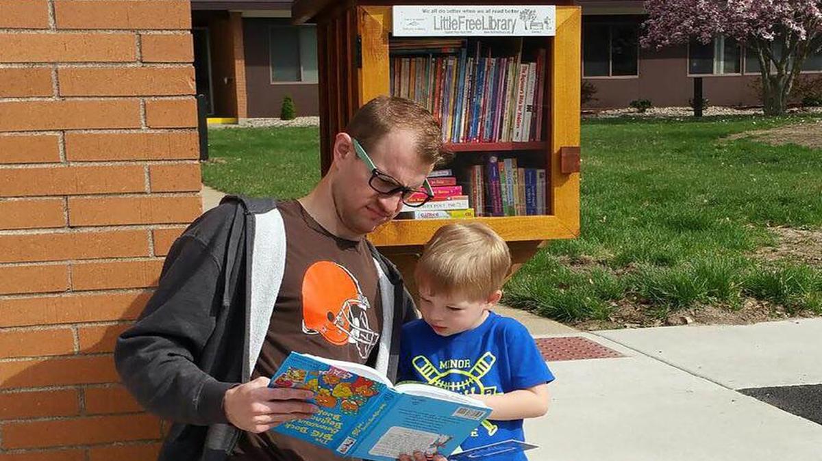 Pastor Will VerDuin and his son Noah check out one of the books available at the recently opened LittleFreeLibrary.