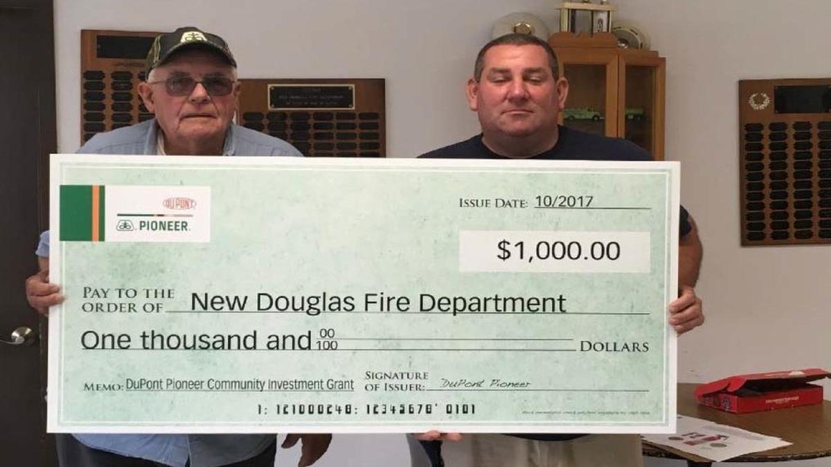 Pioneer sales representative Ron Hemann of New Douglas presents a check to New Douglas Fire Chief Danny Robertson.