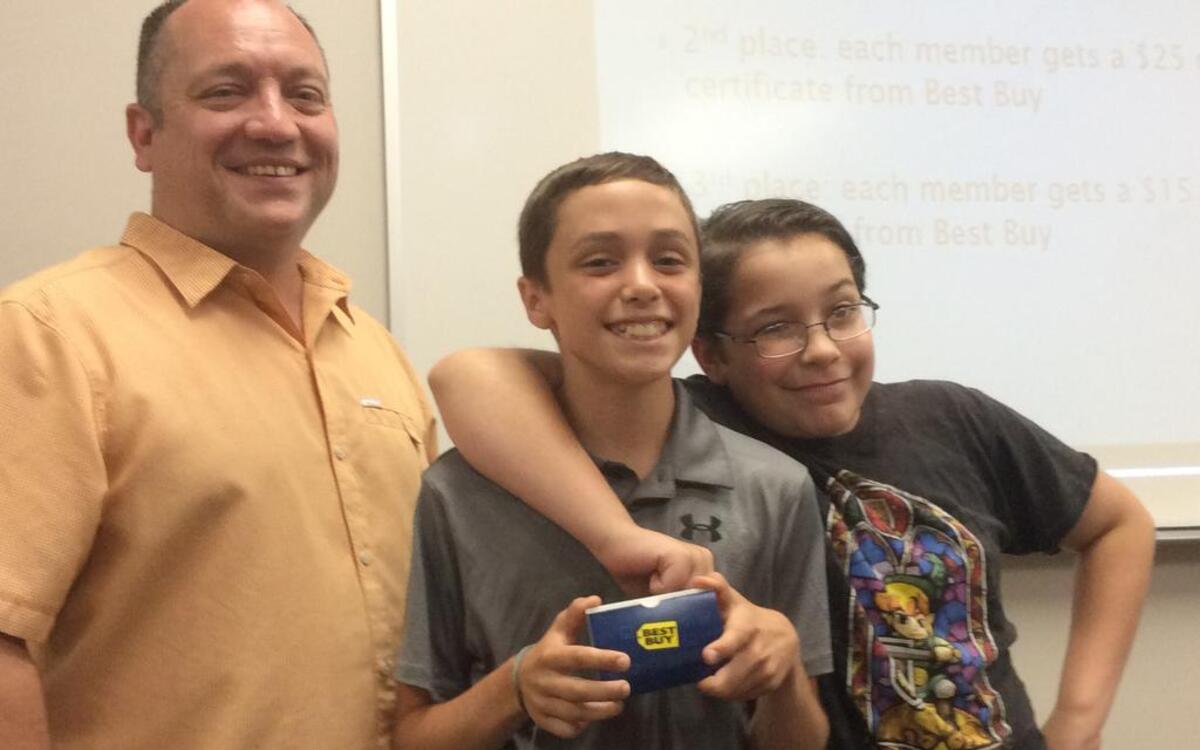 The Junior Code Academy Scratchathon first place team, the Highland Handturkeys. Founder of the JCA Michael Pederson, presents Cole Basden, middle, and Gideon Gaslow with their championship prize, two $50 gift cards to Best Buy. The Scratchathon marked the last session of the summer camp for the JCA. It took place at the Louis Latzer Memorial Library in Highland on June 16. The Handturkeys took first place with a duo Highland themed website, game combination.