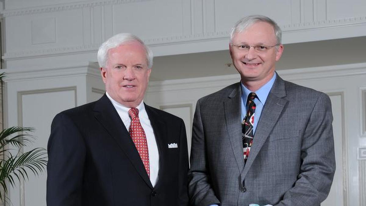 Patrick Sly, executive vice president for Emerson, left, presents Howard Gunning with his Tiffany & Co. crystal apple.
