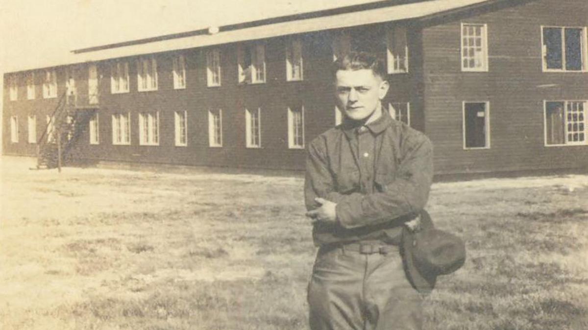 Warren Rutz is shown during World War I, with a barracks in the background.