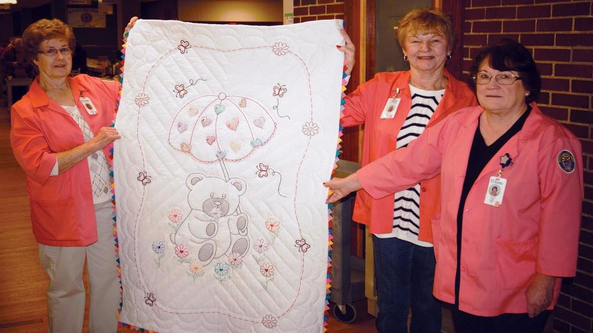 Members of the Auxiliary at HSHS St. Joseph’s in Breese (from left) Jeanette Huelsmann of Breese, Carolyn Crocker of Carlyle and Judith Blaisdell of Albers took a break at the organization’s Used Book Fair and Bake Sale in February to display the baby quilt on the hospital Auxiliary’s Sunday, March 20, Quilt Raffle.