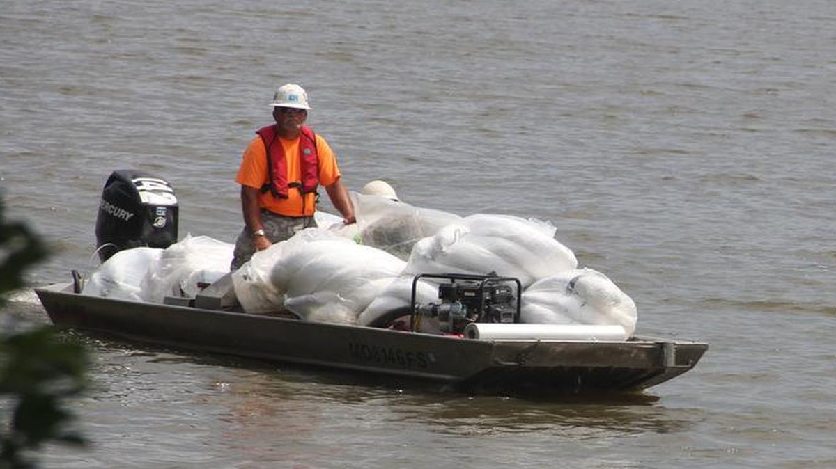 
A Plains All American Pipeline Co. worker brings bags of used absorbent pads to shore late last week in rural Grantfork.
