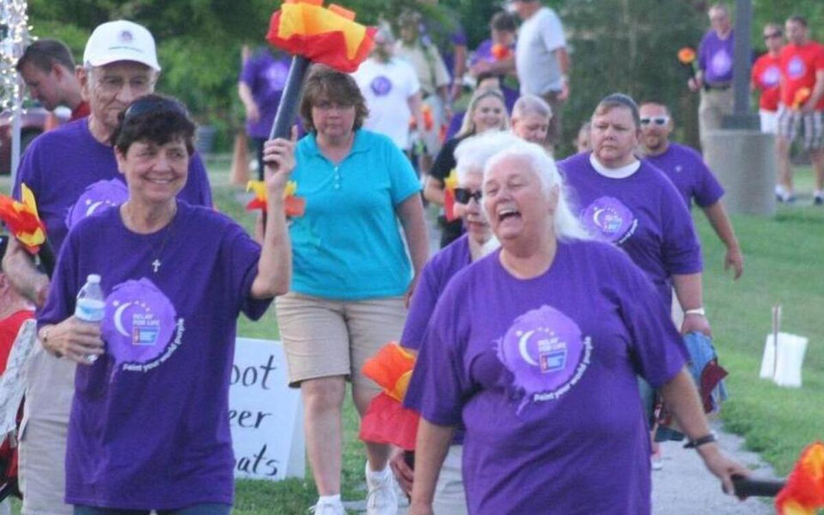 Judith Hamilton and Linda Dunn shared a laugh as they participated in the Survivor/Caregiver Lap during last year’s Relay for Life at Glik Park in Highland. Survivors were given tissue paper torches to carry as part of last year’s Olympics-based theme, “Rings of Hope.”