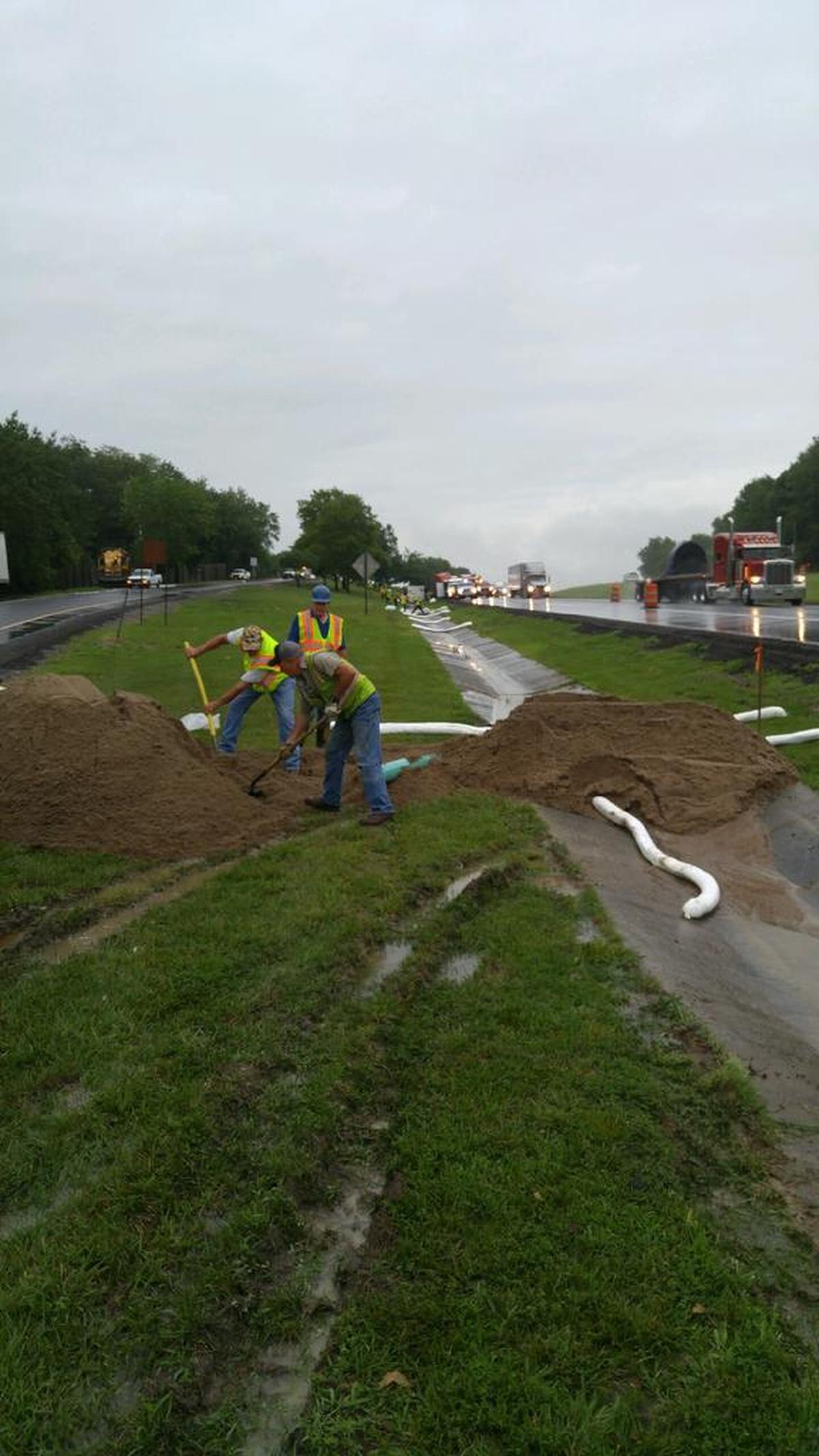 Workers place boom and sand to try and contain a chemical spill caused by a tractor-trailer accident along Interstate 70 near Highland on Thursday.