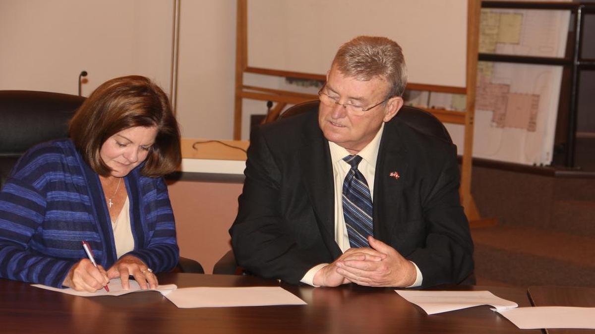 Paula Shea-Calvert signs documents with Highland Mayor Joe Michaelis, establishing the Joe Michaelis Rehabilitative Therapy Scholarship. The $1,000 scholarship will be offered by the Highland Area Community Foundation starting next spring.