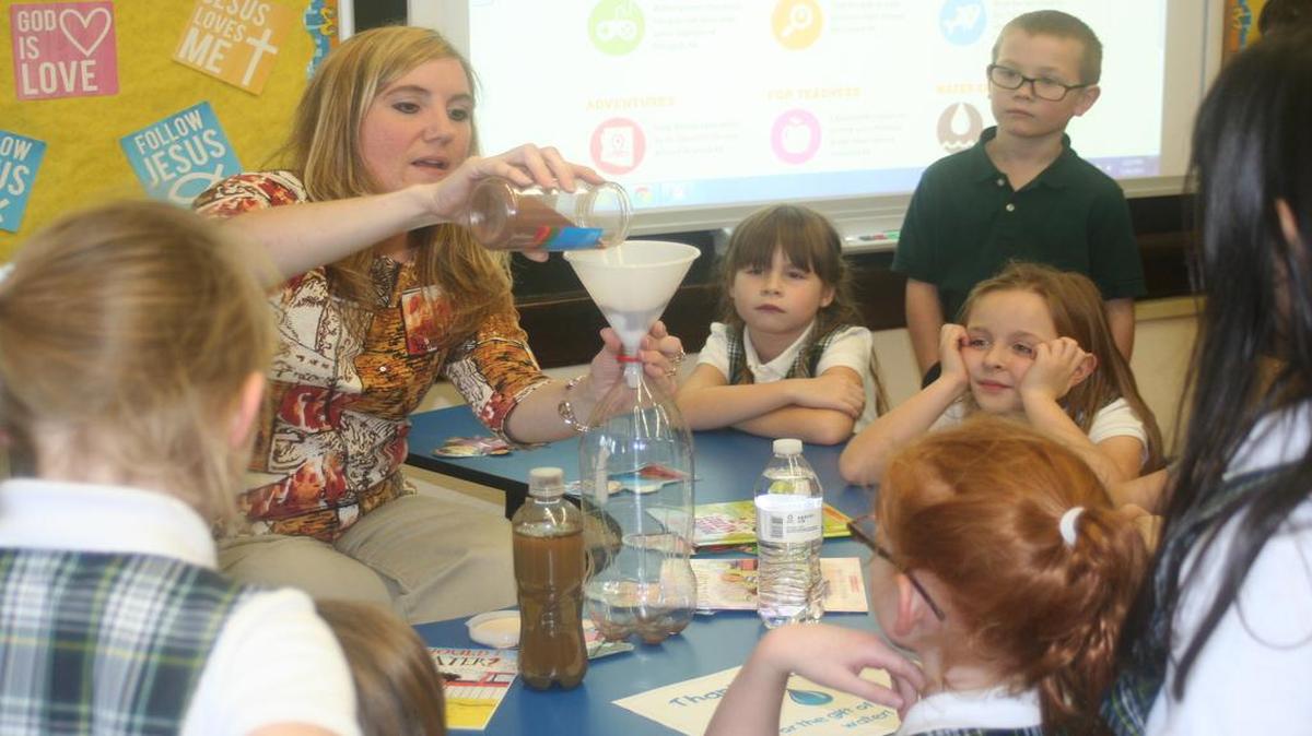 In anticipation of a project for Catholic Schools Week, St. Clare Catholic School teacher Heather Hayden prepares a water filtration experiment as she asks her first-grade students what they expect will happen when she will pour dirty water through the filter. Students on all grade levels will have special projects and lessons about water on one day of the week as they recall their Baptism, learn about the need for clean water throughout the world and explore ways to help people who lack clean water sources.