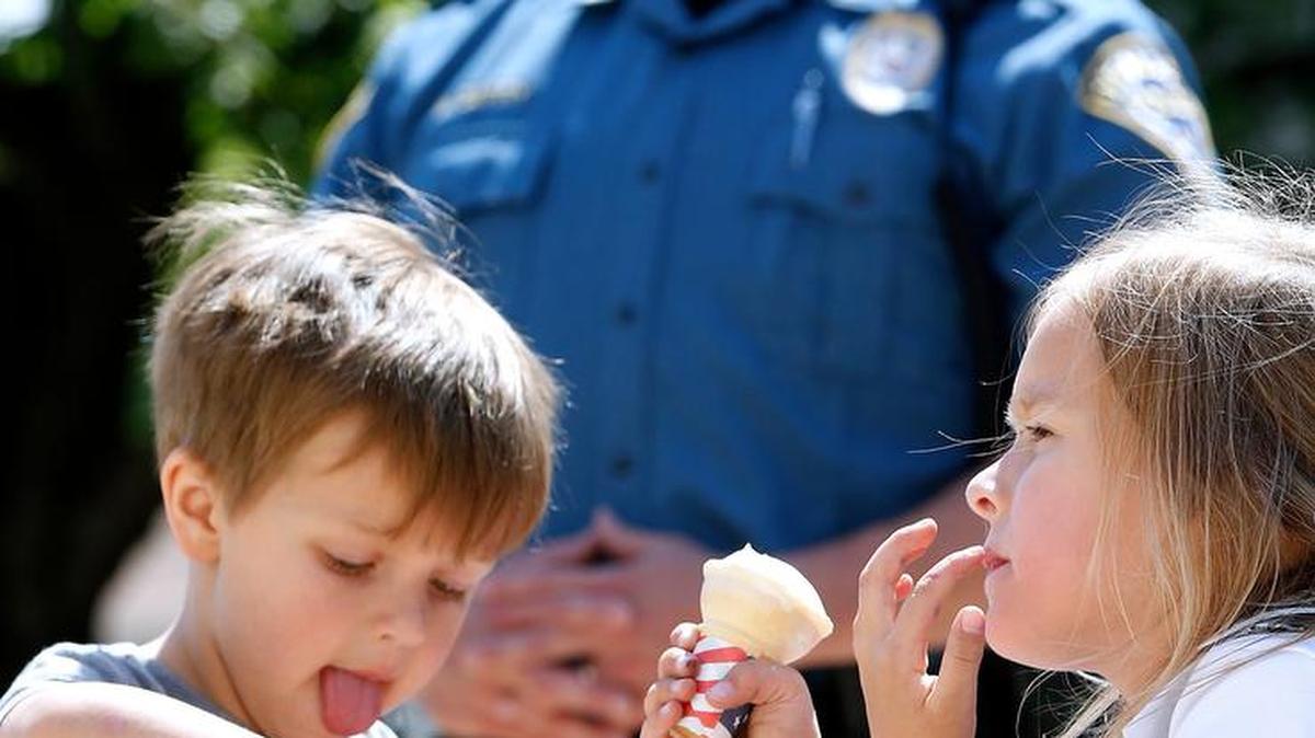 Watkin Olson (left), 3, and sister Avalinn Olson, 5, of O'Fallon dig in to their ice cream Wednesday while O'Fallon Police captain Mark Berry stands by at the I Scream U Scream ice cream shop in O'Fallon. Prairie Farms donated ice cream for cones to kids to come to the shop and mingle with police officers. "We wanted to do something with the kids and continue to build those relationships," said captain Mark Berry.