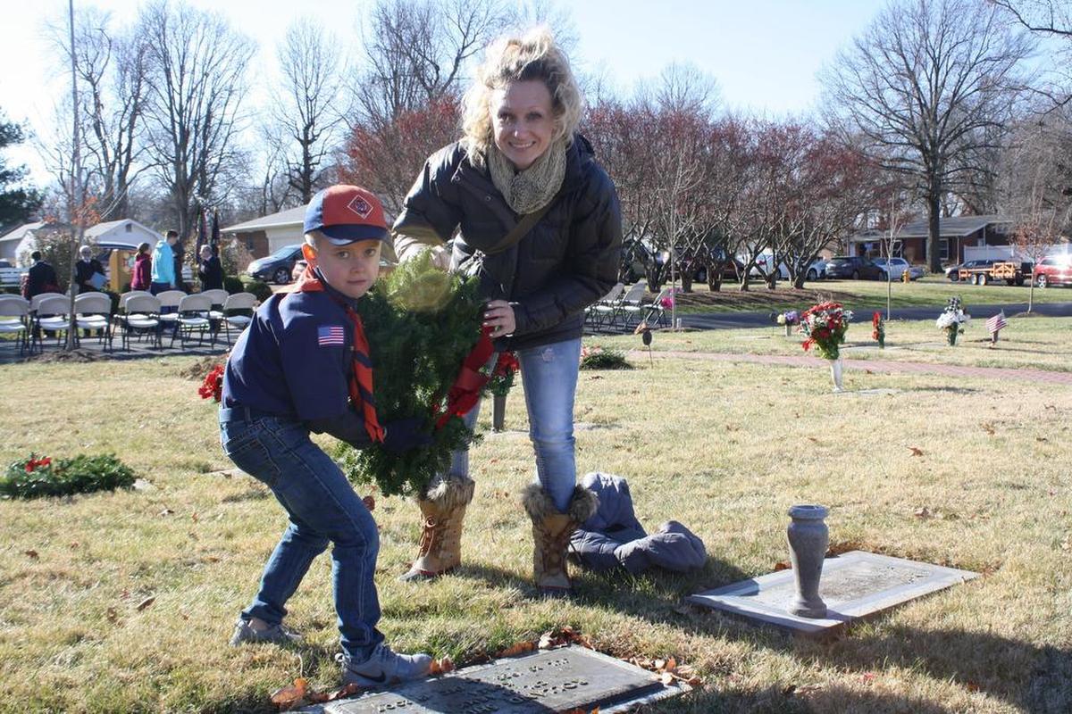 O’Fallon Cub Scout of America Troop 46 Owen Frazier, who also participated in leading the O’Fallon Wreaths of American ceremony attendees in the Pledge of Allegiance, lays a holiday wreath on the gravesite of a veteran Saturday, Dec. 16 as a part of the national program at the O’Fallon Cemetery.